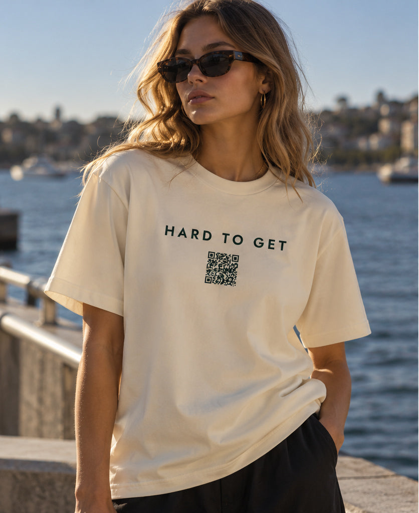 Hard to Get tee in Cream, worn by a model on the harbour