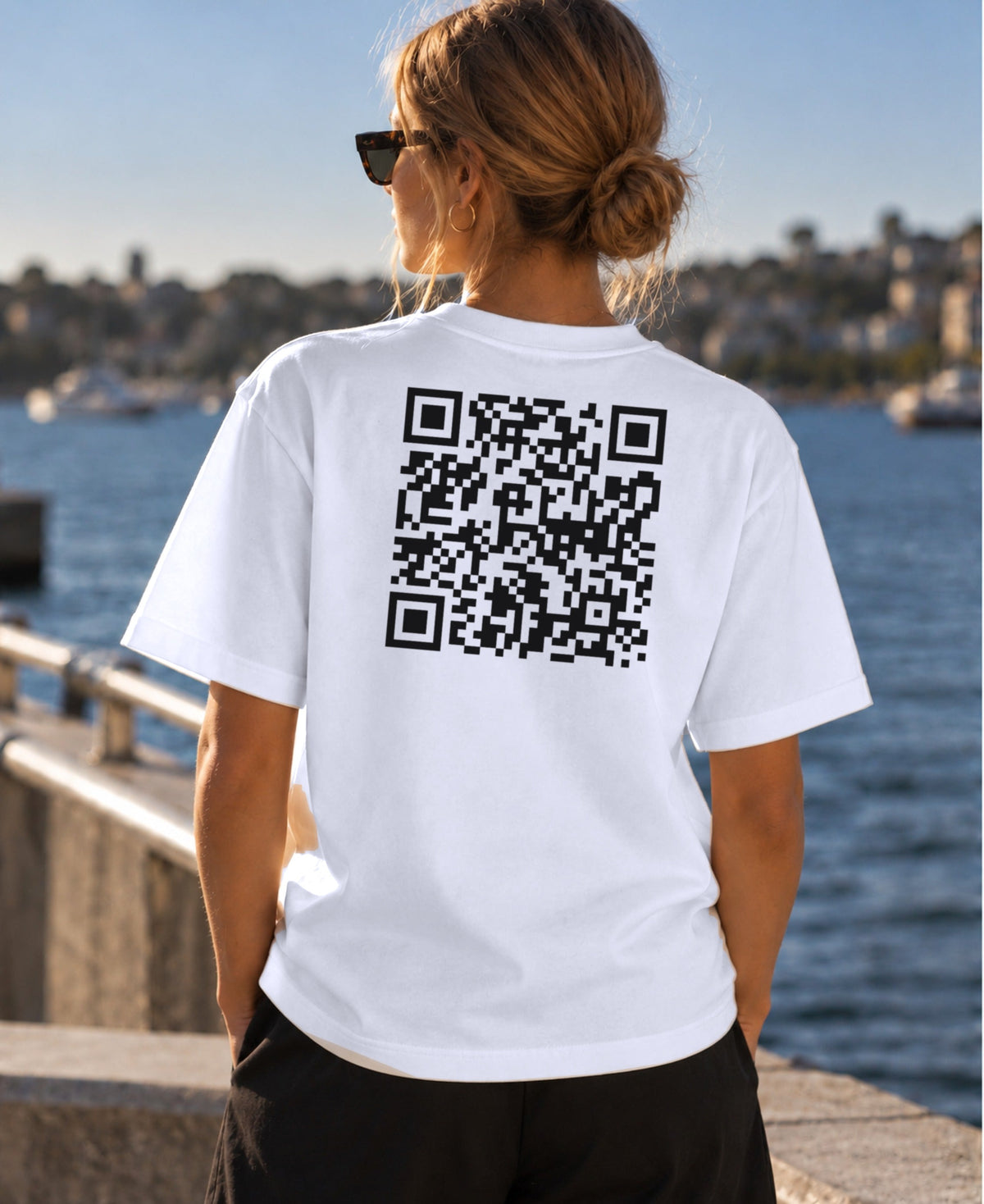 Very Hard to Get tee in White, worn by a model at the harbour, large QR code across the back